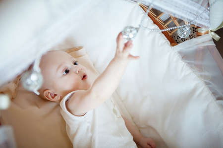 Baby boy lying on the bed and playing toysの写真素材