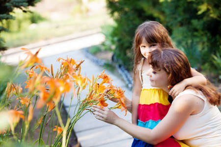 mom and her daughter  play with lilies in the gardenの写真素材