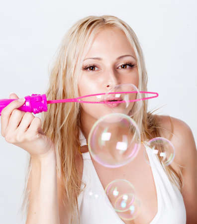 beautiful blonde blowing bubbles on white backgroundの写真素材