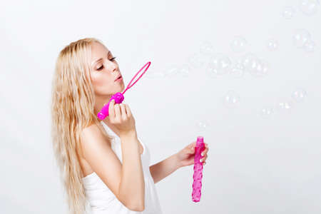 beautiful blonde blowing bubbles on white backgroundの写真素材