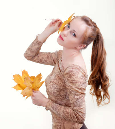 Young beautiful woman with autumn leaves in hands isolated on whiteの写真素材
