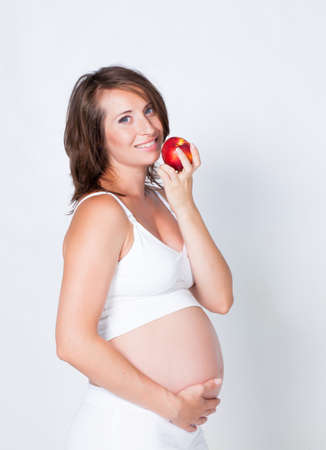 Pregnant woman with apple in studioの写真素材