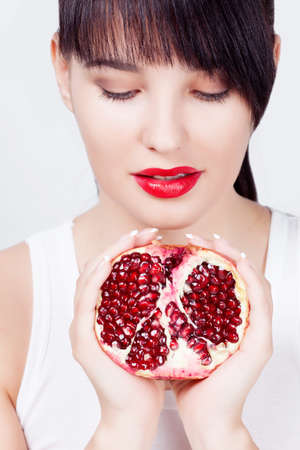 Brunette girl with garnet fruit in studioの写真素材