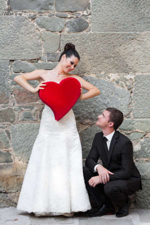 Bride and groom outdoor portrait with red heartの写真素材