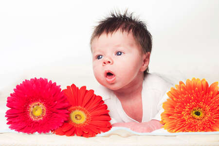 Infant lying on a blanket with gerber a flowersの写真素材