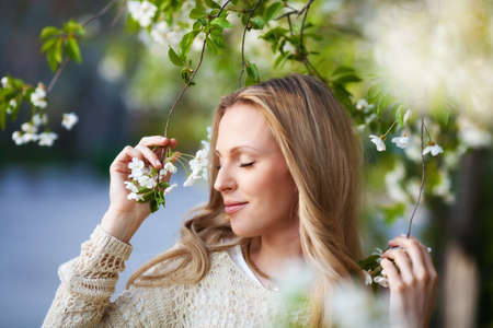 Beautiful blond woman portrait near cherry blossom treeの写真素材