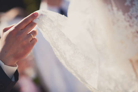 Groom hand holding bride dress by fingersの写真素材