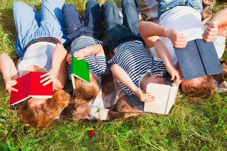 Family reading books laying on the grassの写真素材