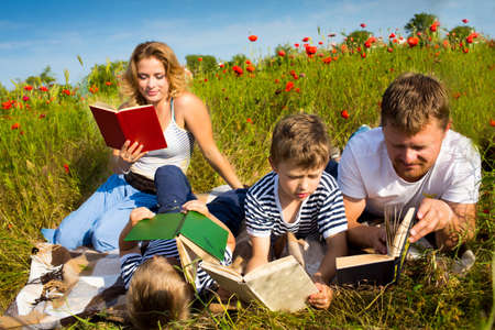 Family reading books laying on the grassの写真素材