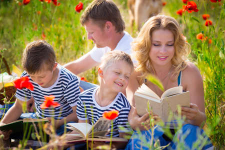 Family reading books laying on the grassの写真素材