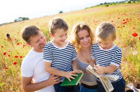 Family with books in hand on the poppy meadowの写真素材