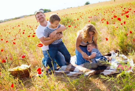 Family with books in hand on the poppy meadowの写真素材