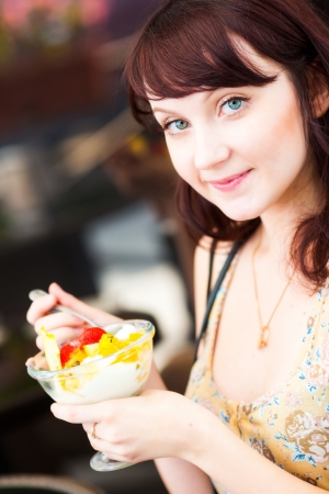 Young woman eating ice-cream in cafeの写真素材