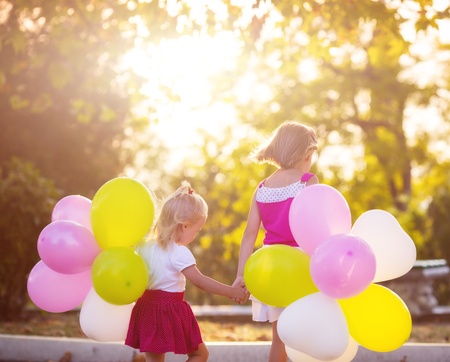 Two little girls with balloons in the parkの写真素材