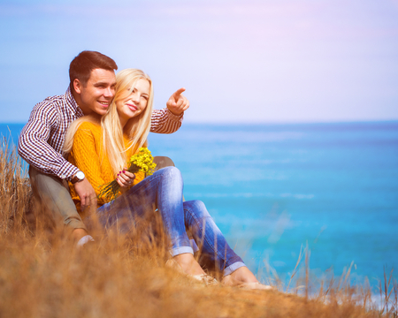Happy man and woman seating on the seashoreの写真素材