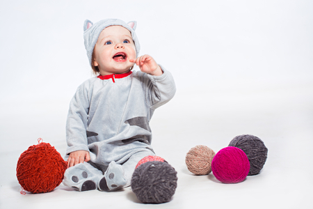 Little boy in cat costume playing with balls of woolの写真素材