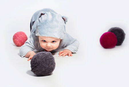 Little boy in cat costume playing with balls of wool