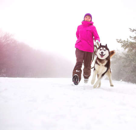 Beautiful girl walking with husky dogの写真素材