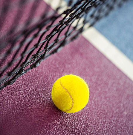 Tennis ball on the ground near the netの写真素材