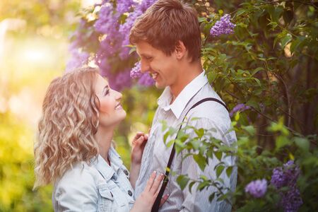 Two lovers in summer garden near blossom lilac flowersの写真素材