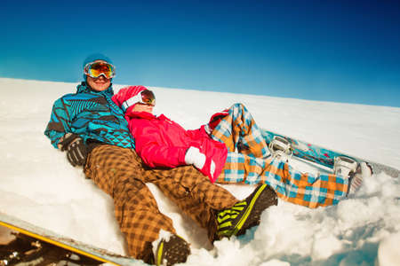 Girl and boy with snowboards on the snowの写真素材