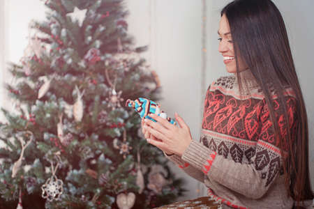 Beautiful young woman with present near christmas treeの写真素材