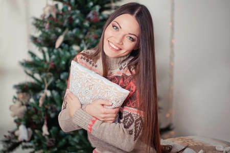 Beautiful young woman with present near christmas treeの写真素材