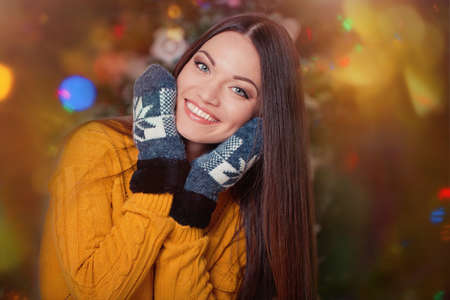 Beautiful young woman in winter clothes near christmas treeの写真素材