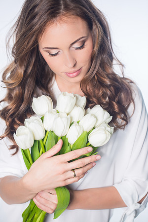 Young beautiful woman studio portrait with tulip flowersの写真素材