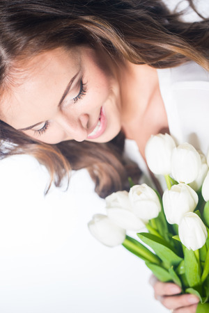 Young beautiful woman with bouquet of tulip flowers, portrait in studioの写真素材