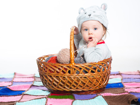 Little boy dressed as a cat sitting in basket with balls of woolの写真素材