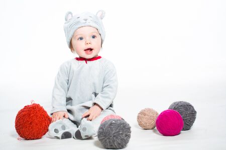Little boy dressed as a cat sitting with balls of woolの写真素材