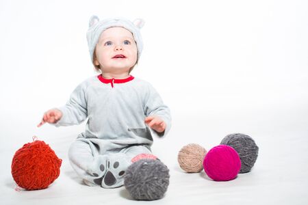 Little boy dressed as a cat sitting with balls of woolの写真素材
