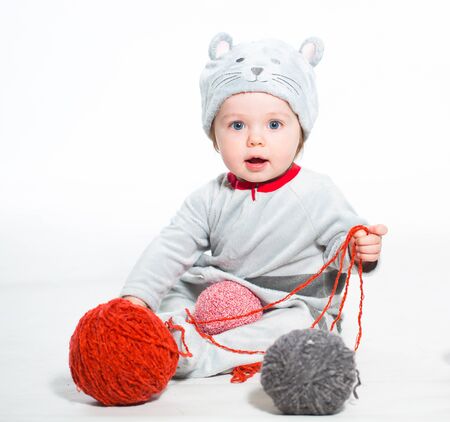 Little boy dressed as a cat sitting with balls of woolの写真素材