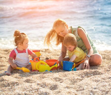 Mother playing with children on the beachの写真素材