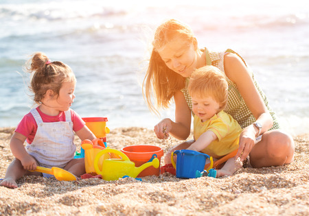Mother playing with children on the beachの写真素材