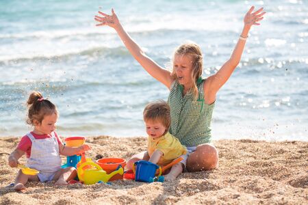 Mother playing with children on the beachの写真素材