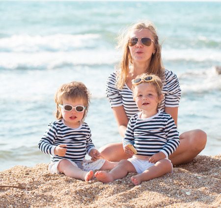 Mother playing with children on the beachの写真素材