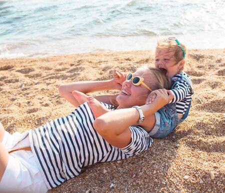 Mother playing with daughter on the beachの写真素材