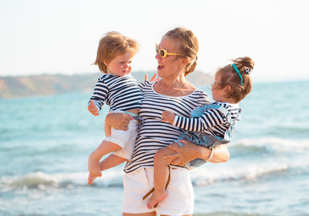 Mother playing with children on the beachの写真素材