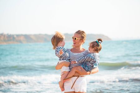 Mother playing with children on the beachの写真素材