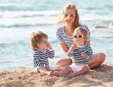 Mother playing with children on the beachの写真素材