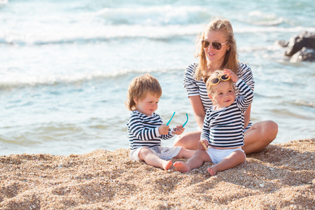 Mother playing with children on the beachの写真素材