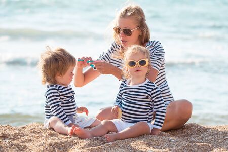 Mother playing with children on the beachの写真素材