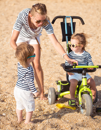 Mother playing with children on the beachの写真素材