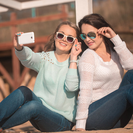 Young beautiful girls taking self photo by cellphoneの写真素材