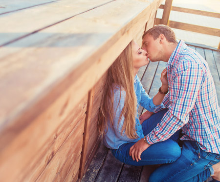 Young couple outdoor portrait. Beautiful pretty girl kissing handsome boy. Sensual photoの写真素材