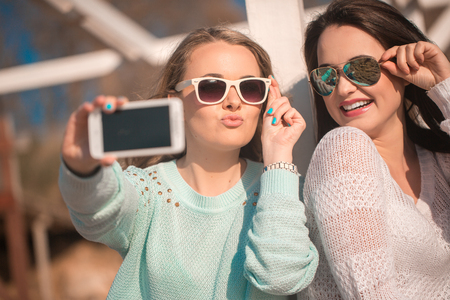 Young beautiful girls taking self photo by cellphoneの写真素材