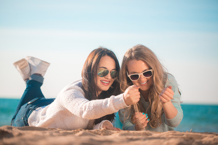 Two girls resting on the autumn beachの写真素材