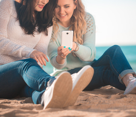 Two girls resting on the autumn beachの写真素材